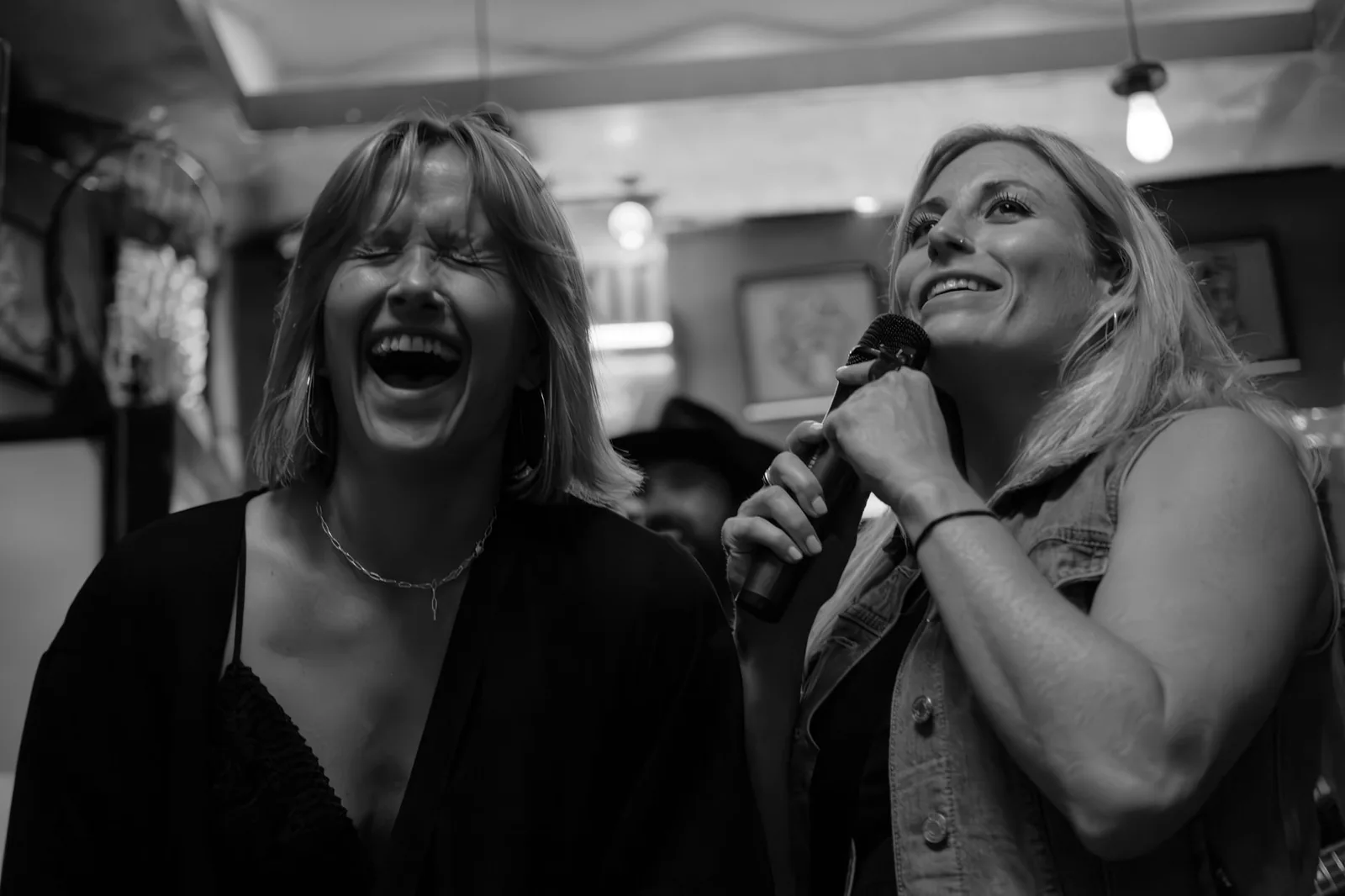 Karaoke veče u baru sa mikrofonom i publikom koja peva omiljene hitove svih vremena