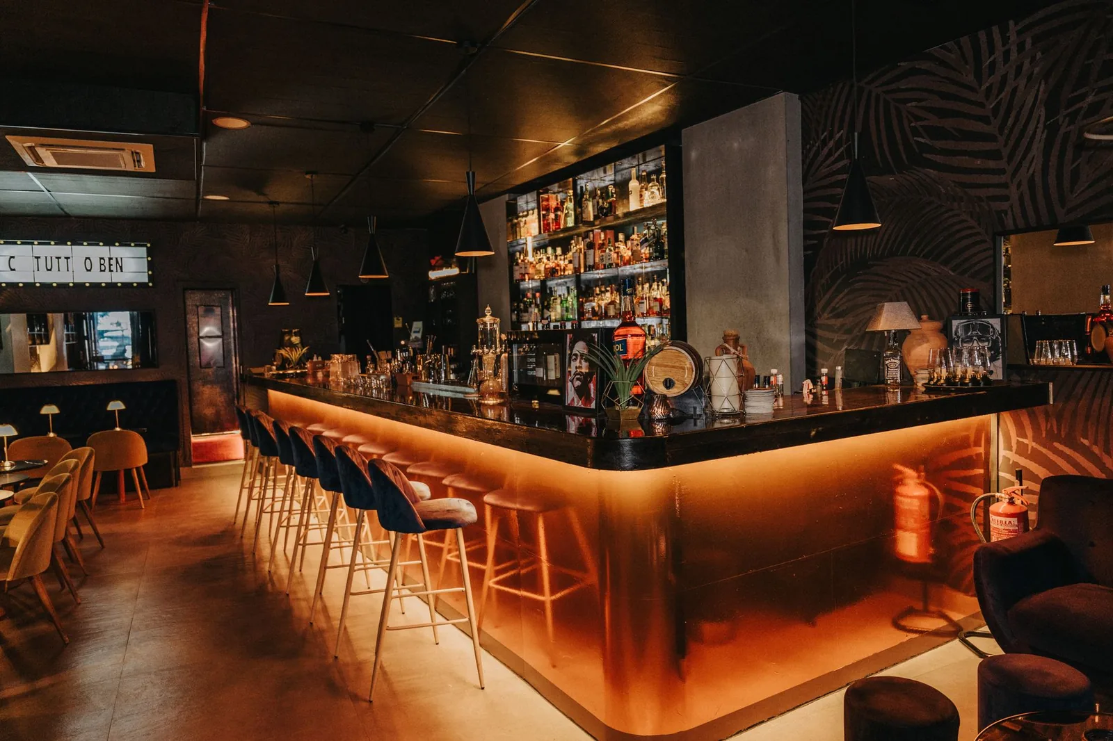 Tematska večer u lounge baru sa atmosferskim osvetljenjem i gostima koji uživaju